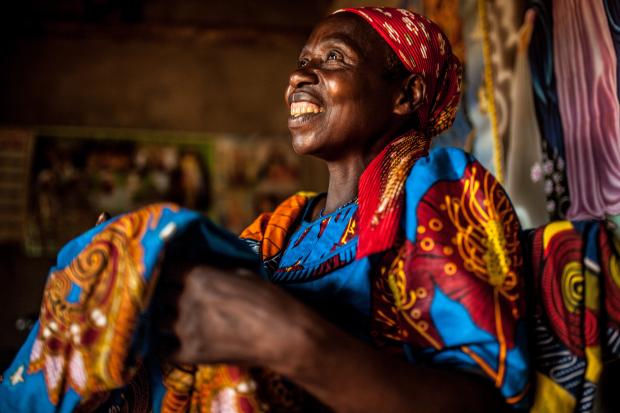 Theresie Nyirantozi (60 yrs) admires tailored fabric she purchased in her home in Kirehe District, Eastern Rwanda. 